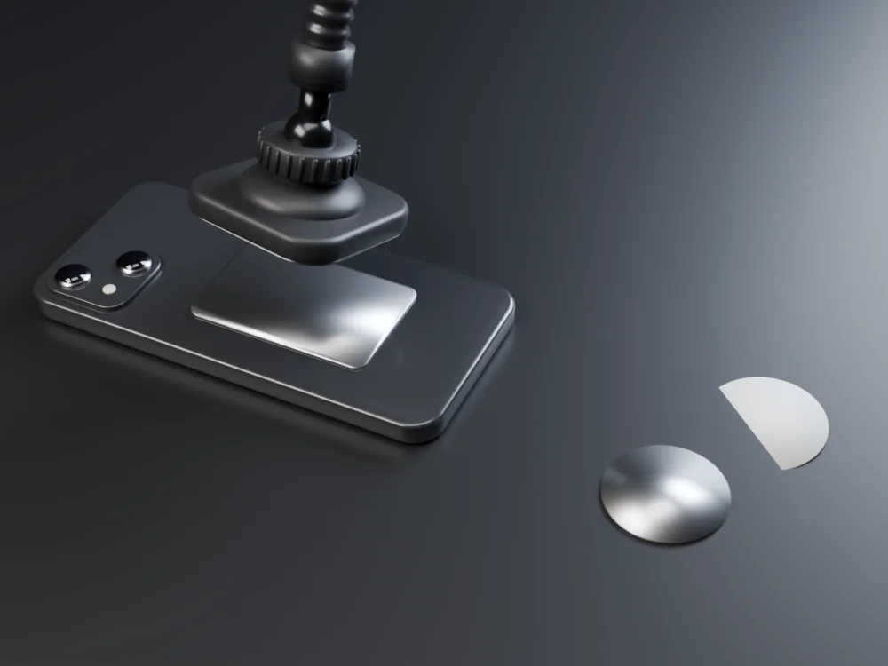 An original 3D render of a phone lying face down with a thin rectangular metal plate stuck on its back and the mount's square magnetic head coming down onto it. A round plate lies beside it, its backing peeled off.